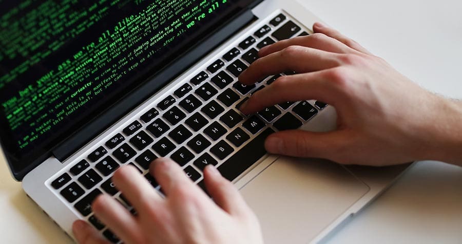 mão digitando em um laptop realizando um cyber ataque